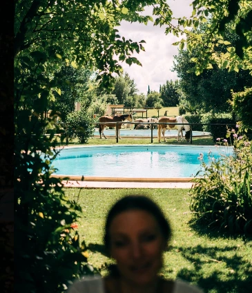 Selfie di una signora in un agriturismo, sullo sfondo piscina bio e cavalli