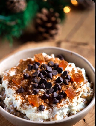 Coppa con all'interno la cuccia, dolce di Santa Lucia. grano cotto, ricotta cremosa, cannella in abbondanza, gocce di cioccolato e canditi colorati, in un’atmosfera festiva di dicembre.