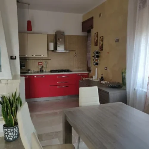 Cucina spaziosa con mobili rossi e bianchi, camino in pietra e zona pranzo luminosa presso Masserie Germano a Rotondella MT